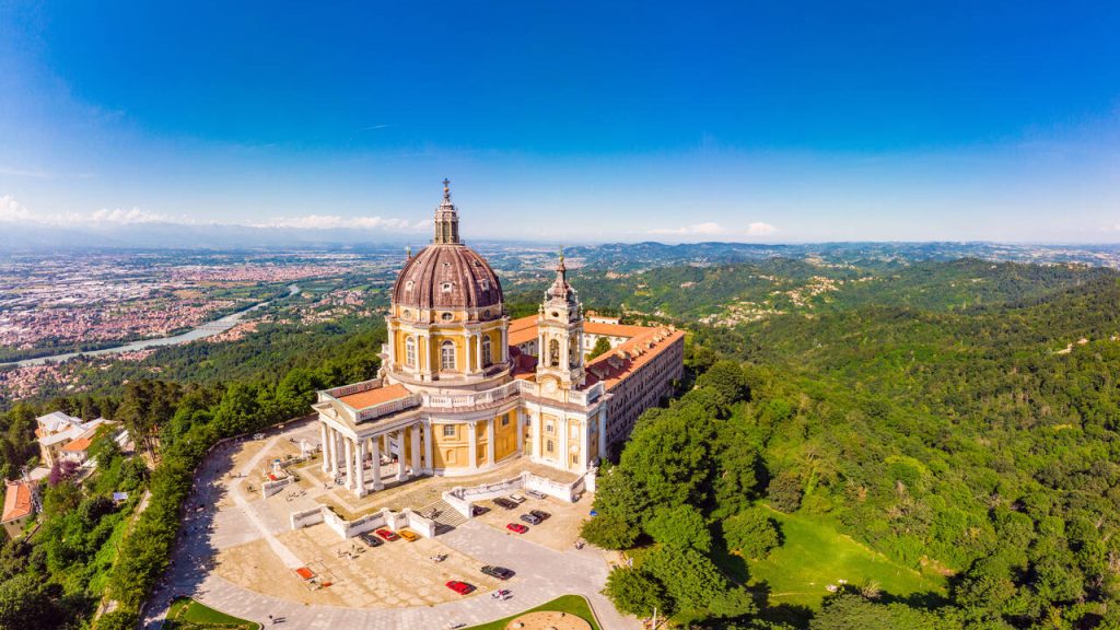 Beautifull aerial panoramic view to the famous white orange Basilica of Superga in a sunny summer day. The cathedral church located at the top of hill in italian Alps mountains. Turin, Piedmont, Italy. Promised by Vittorio Amedeo II of Savoy in 1706 and designed by Juvarra. where the plane of the Grande Torino crash of Turin Football Club happened, in 1949.
